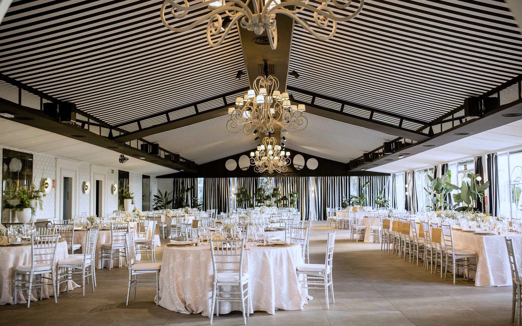 El Salon Colonial en simetria bajo la lampara central, con el techo de rayas y el banquete montado