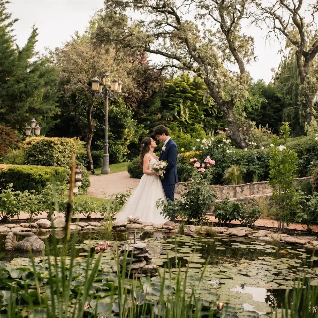 Novios besándose junto al estanque · jardín de la finca