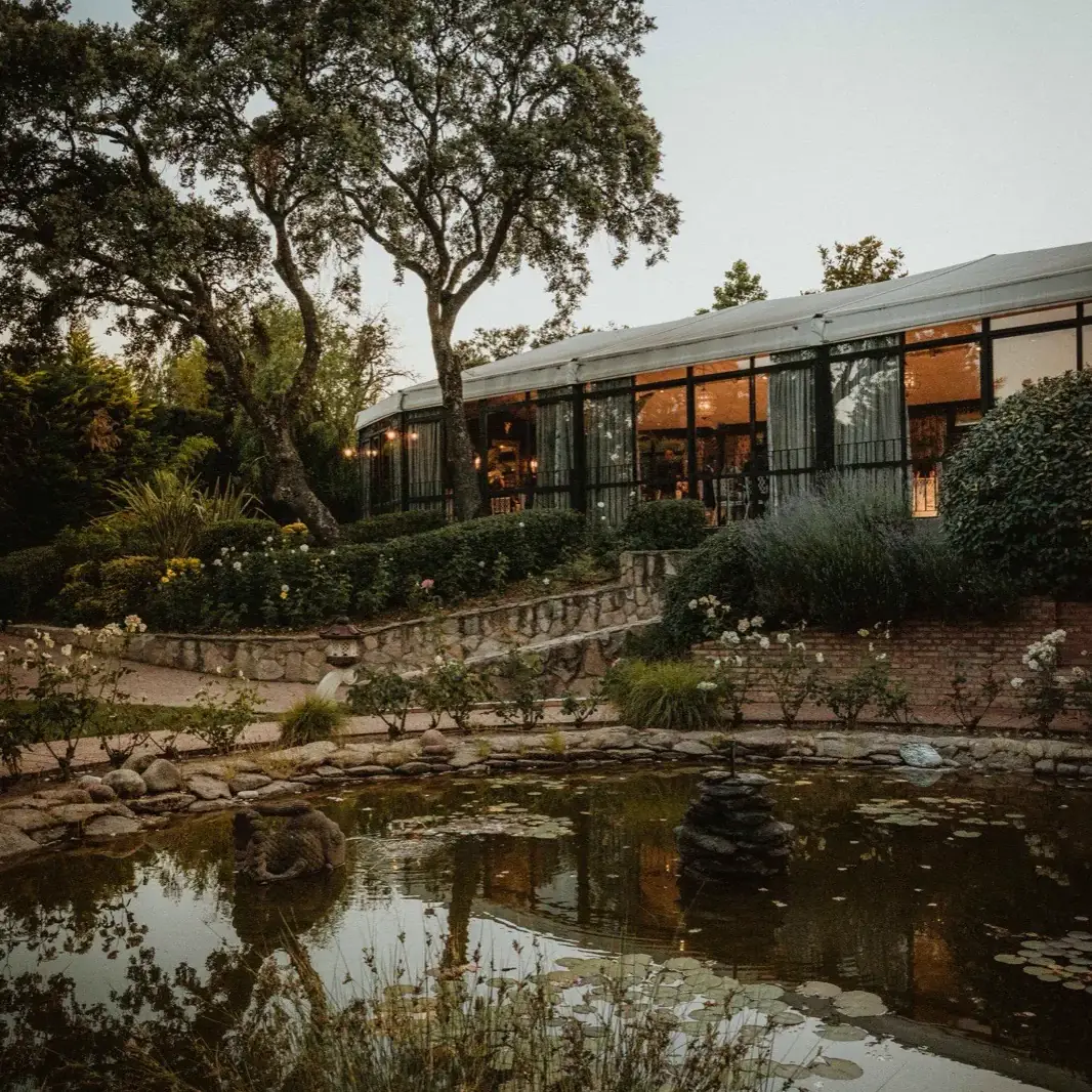 Pabellón al atardecer · jardín, estanque y ventanal iluminado