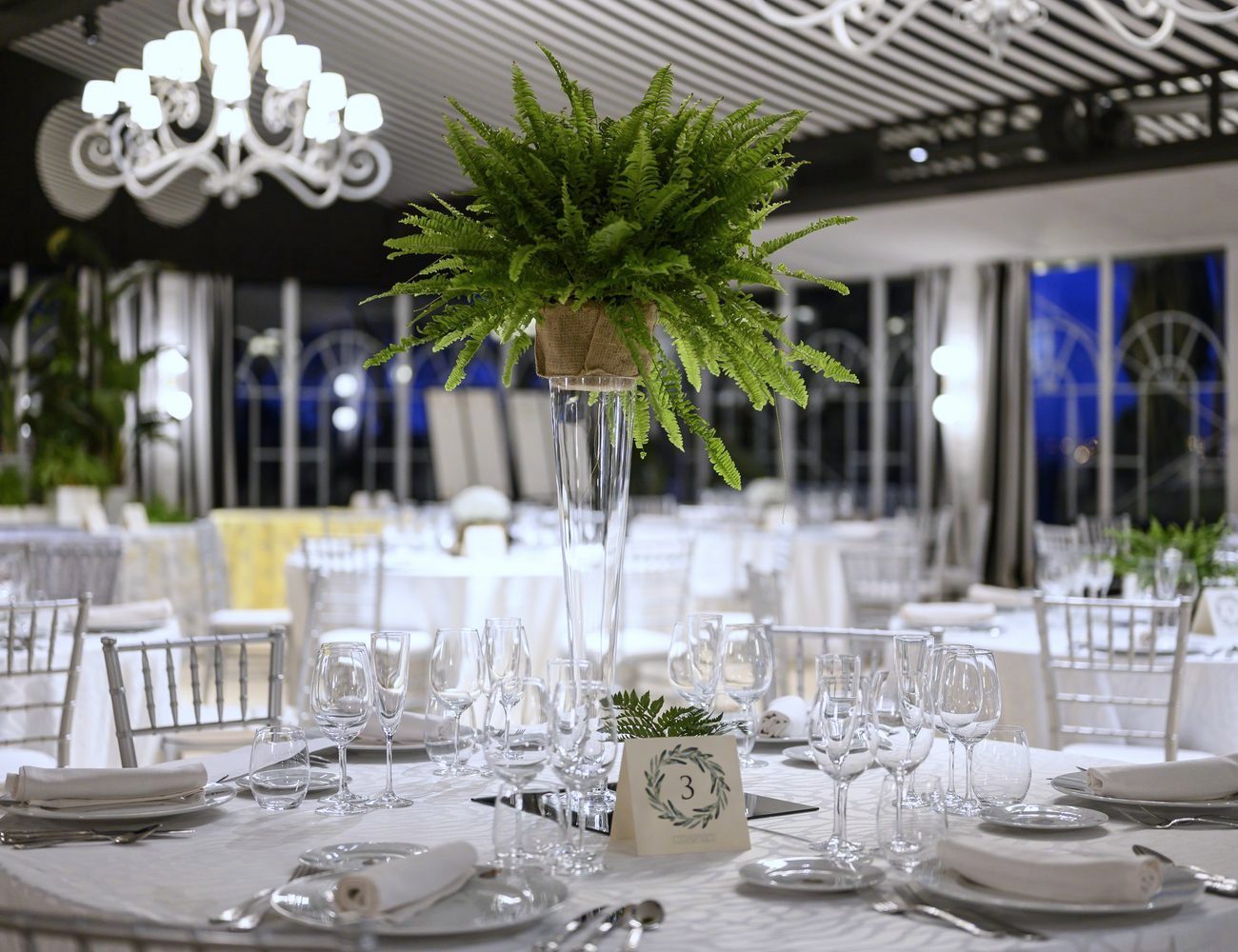 Detalle de mesa vestida con el helecho en alto y la lampara de globo, la artesania del Invernadero